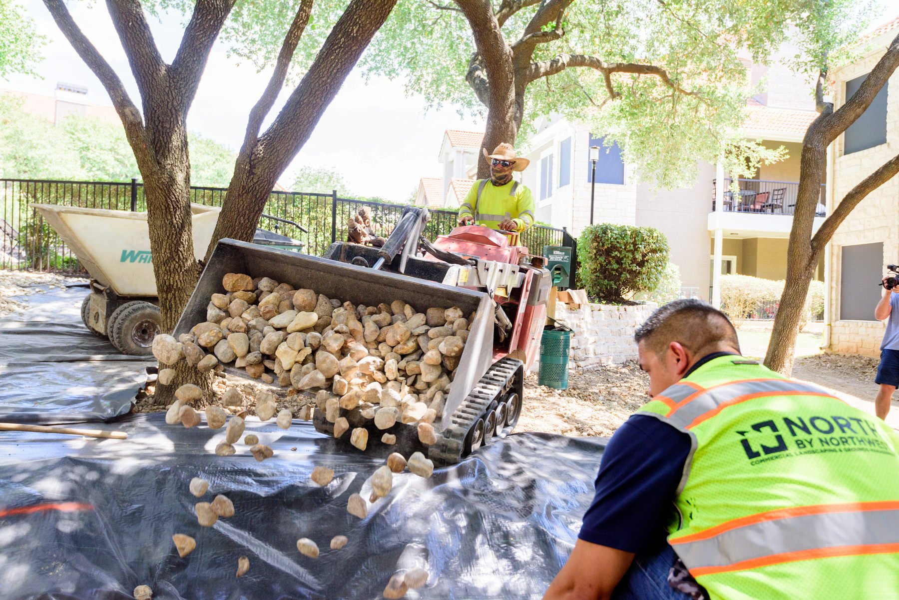 Landscaping crew installing stone on top of erosion control fabric