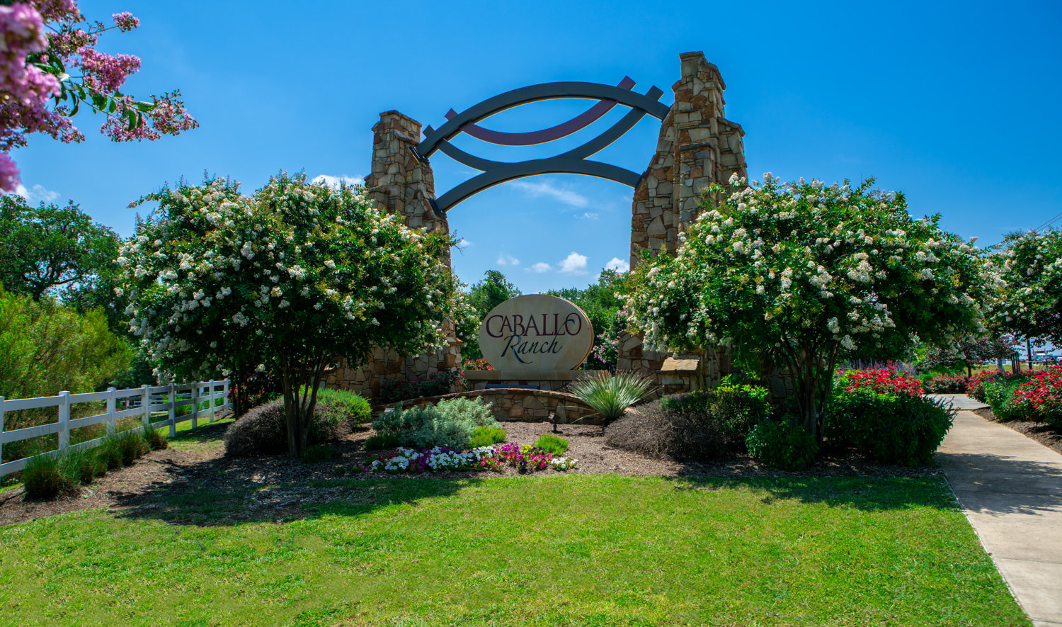 Trees, shrubs, and flowers around apartment complex sign