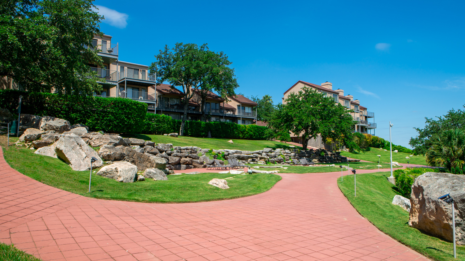 commercial-landscaping-VillasAtTravis-hill-walkway-grass-stonewall-trees-1